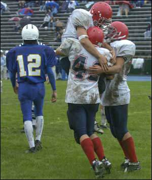 Jason Gildea and Tom McMillen celebrate the win with Joe Nicholson, front, who scored a fourth-quarter touchdown to tie the game at 16 all.